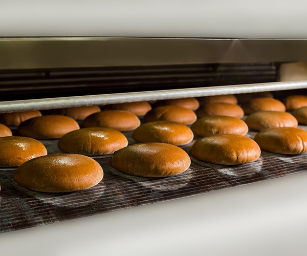 Loaves of bread on the production line in the bakery. Bread production process at food factory. Food industry.